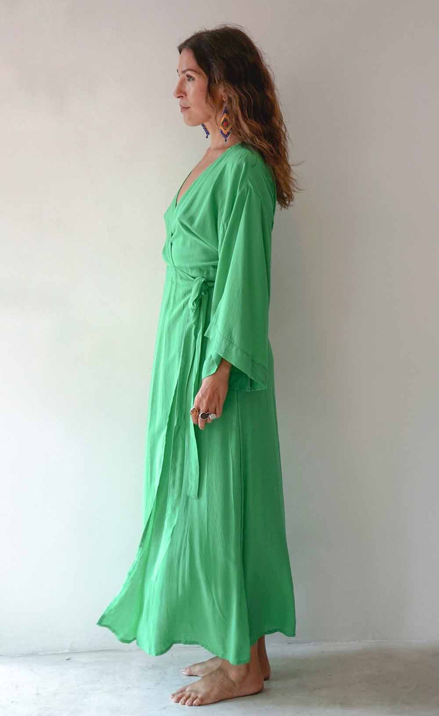 Woman wearing a green dress standing against a plain background