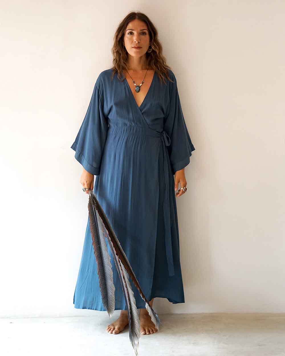 Woman wearing a blue dress holding a scarf against a white background