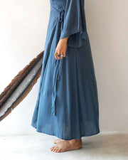 Person wearing a long blue dress standing against a neutral background
