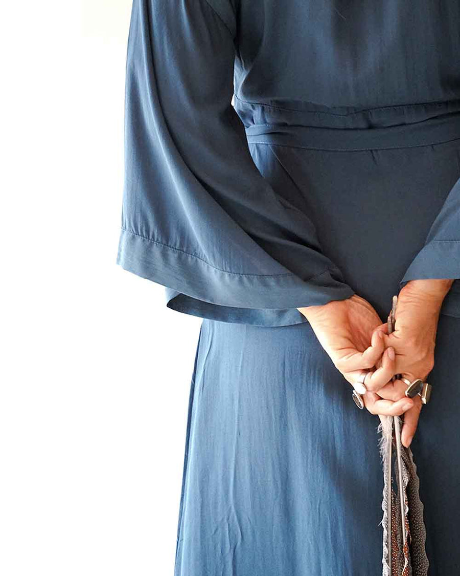 Person wearing a blue outfit holding a small object against a white background