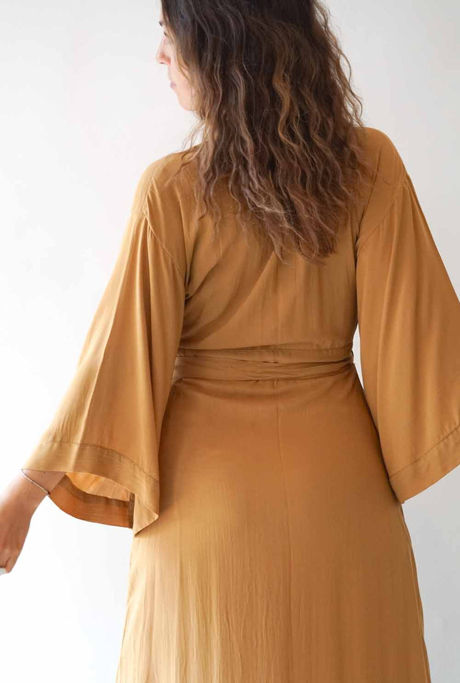 Woman wearing a mustard yellow dress with a plain white background