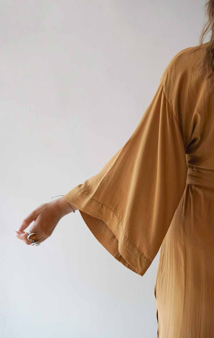 Person wearing a mustard yellow dress against a white background