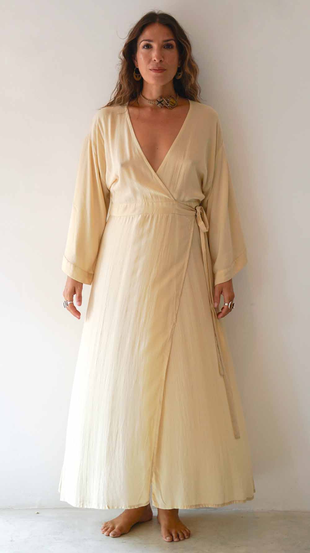 Woman wearing a long, light-colored dress against a white background