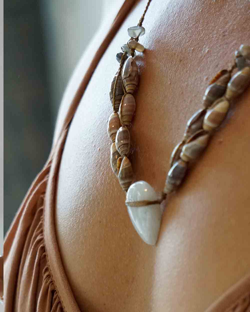 Necklace with shell and stone beads on a person's neck