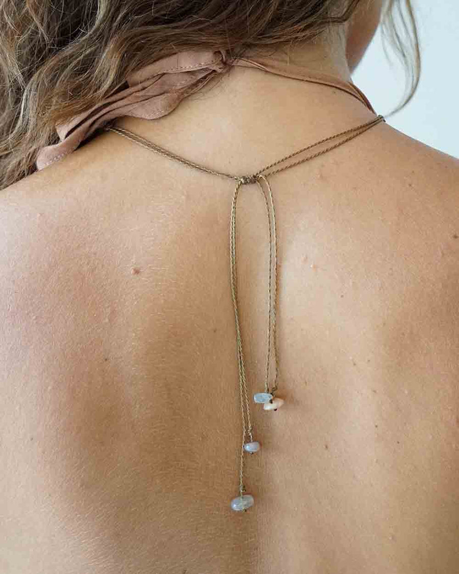 Necklace with stones draped over a person's shoulder against a neutral background