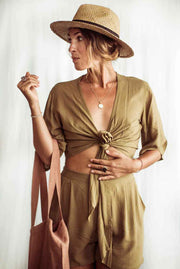 Woman wearing a beige outfit with a hat against a white background