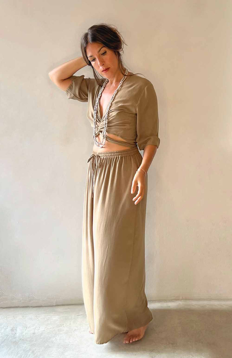 Woman wearing a beige outfit with a plain background