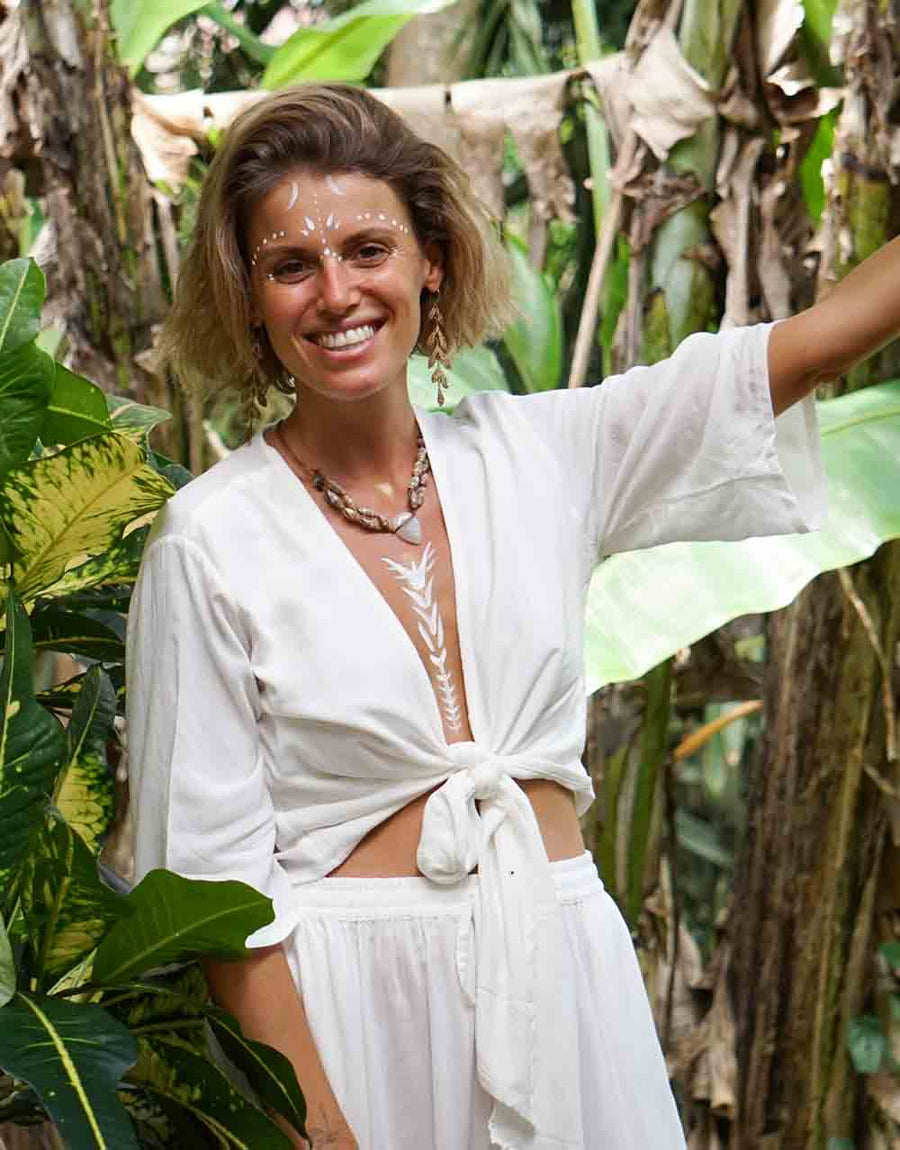 Woman in a white outfit standing among tropical plants