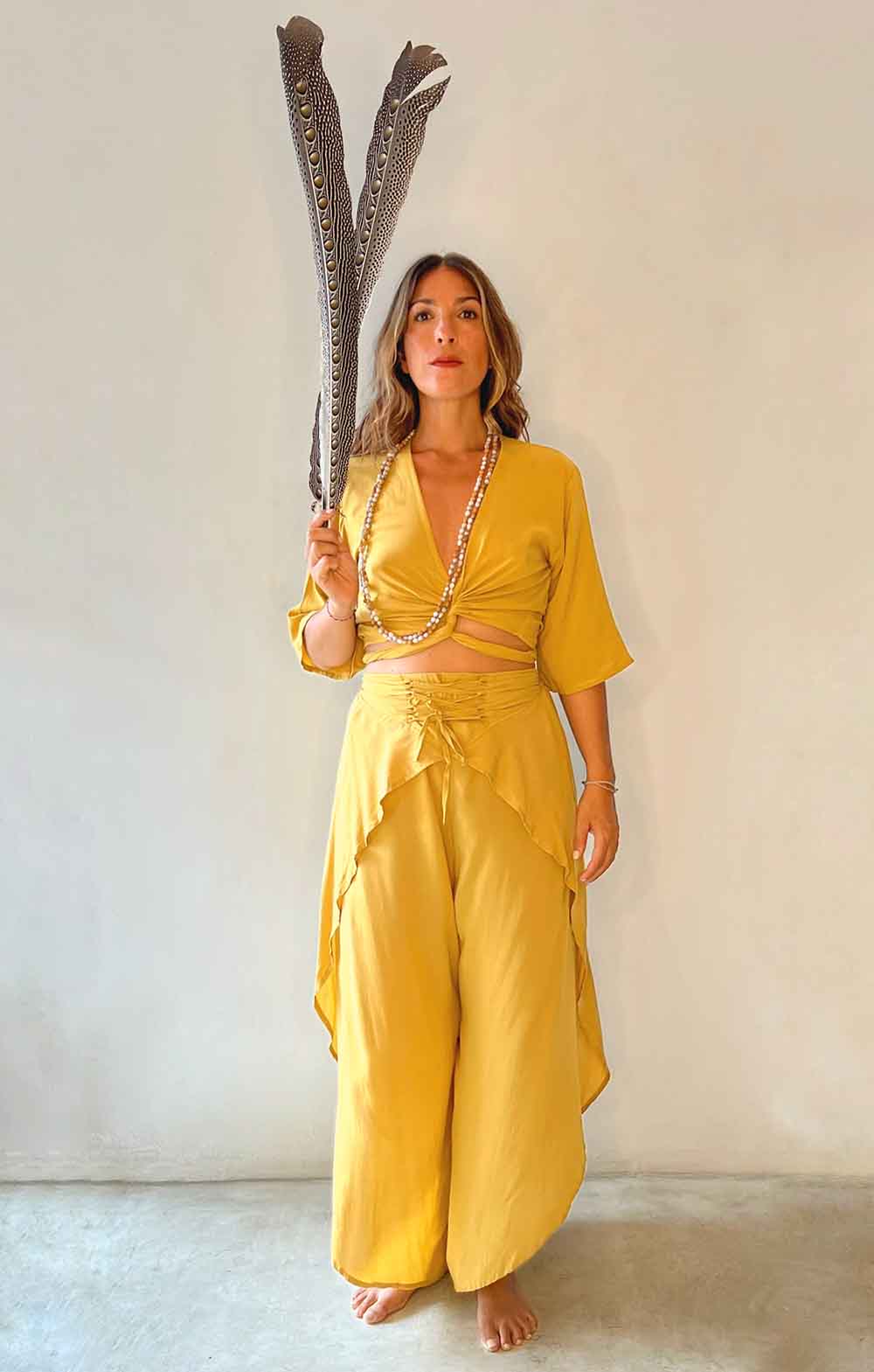 Woman in a yellow outfit holding a large decorative item against a plain background