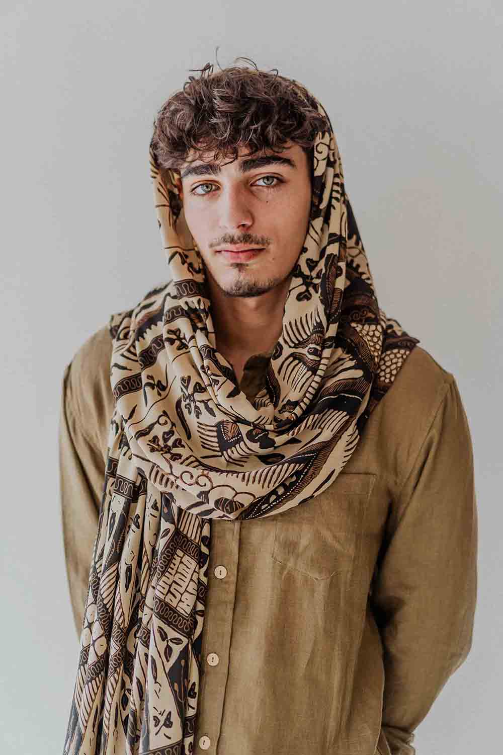 Man wearing a patterned scarf on a plain background