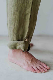 Person wearing green pants with a button on a plain background