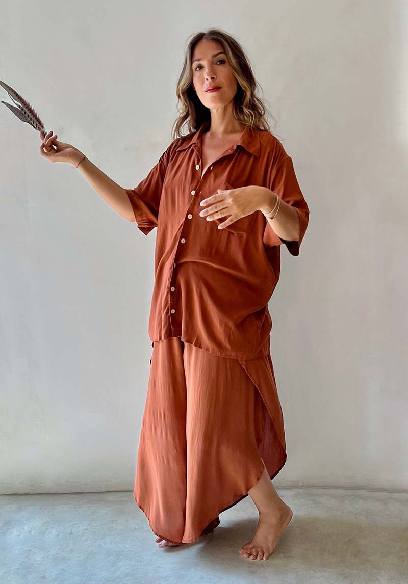 Woman wearing a brown outfit holding a knife against a plain background