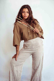 Woman wearing a brown shirt and striped pants holding a bow and arrow against a white background