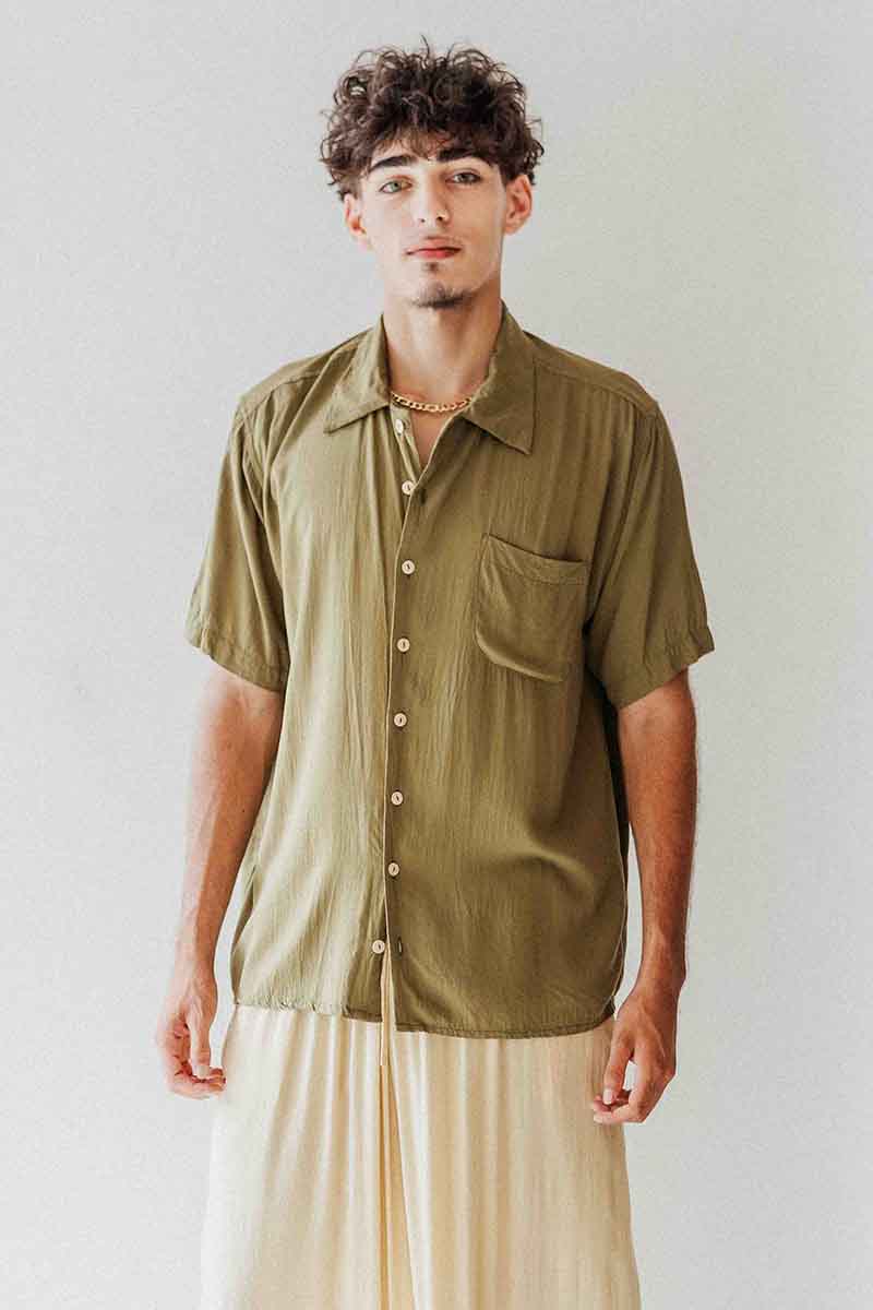 Man wearing a green button-up shirt with a plain background