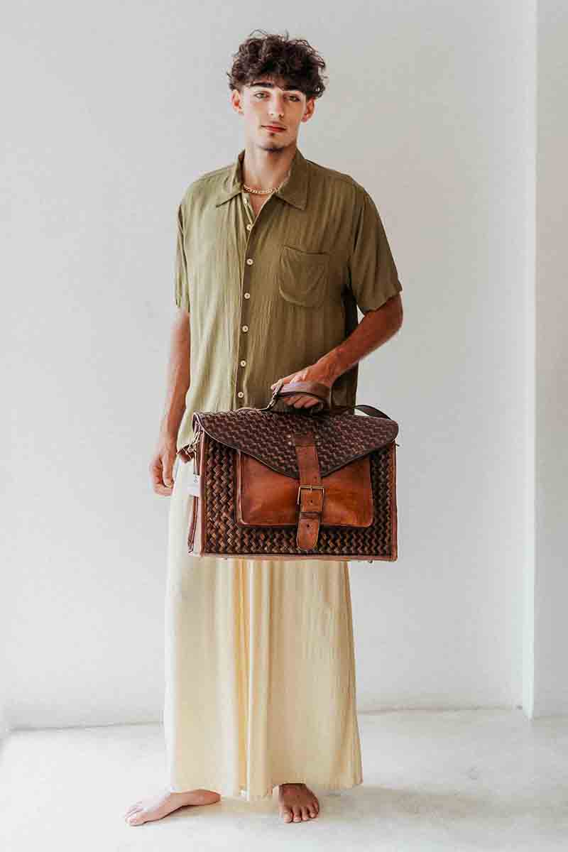 Man holding a woven leather bag against a white background