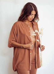 Woman wearing a brown outfit holding dried flowers against a white background