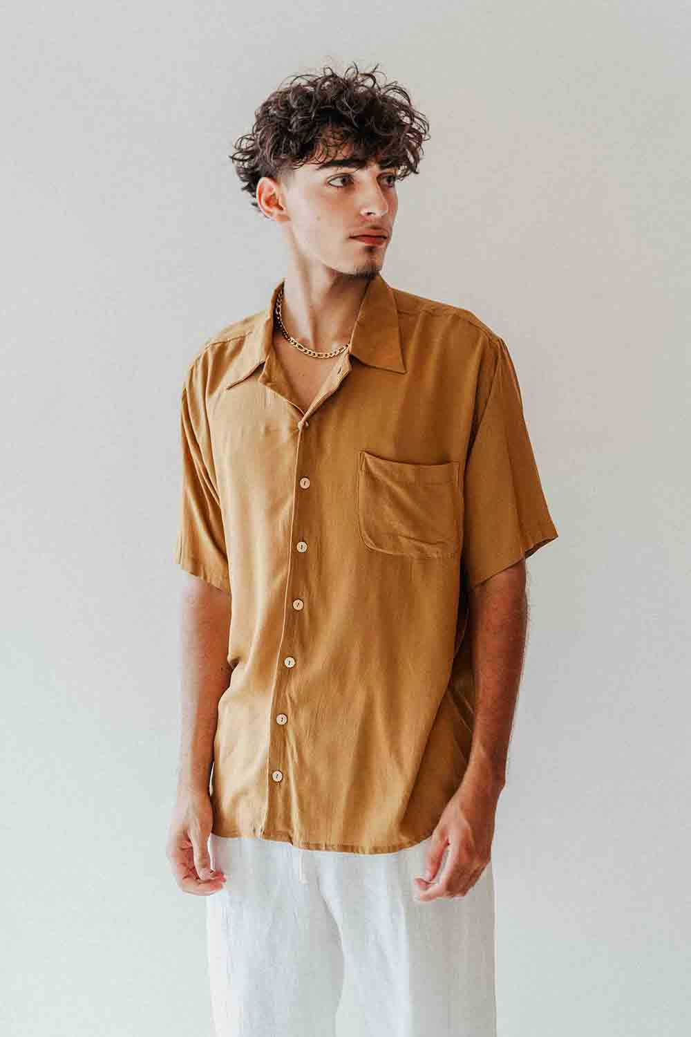 Man wearing a mustard yellow shirt against a plain background