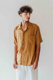 Man wearing a mustard yellow shirt against a plain background