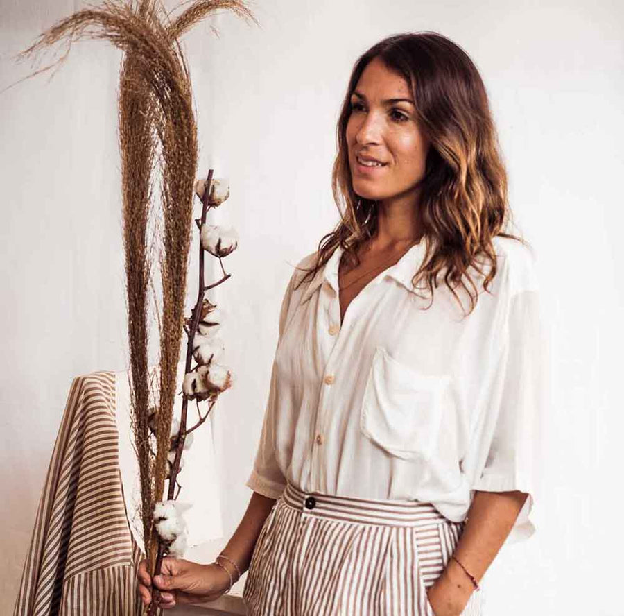 Woman holding a cotton plant against a plain background