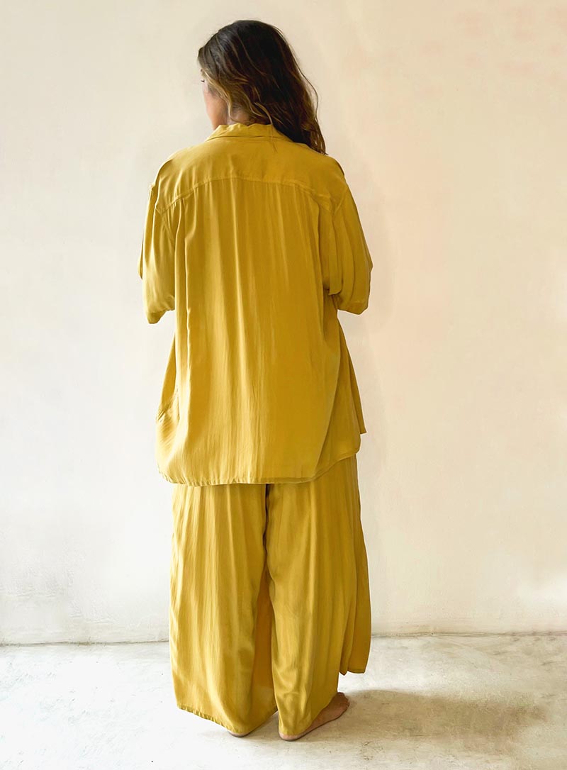 Person wearing a mustard yellow outfit against a plain background