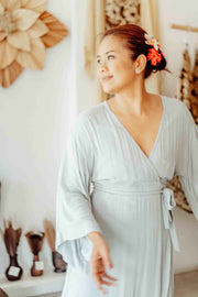 Woman in a light gray robe standing in a room with decorative elements.