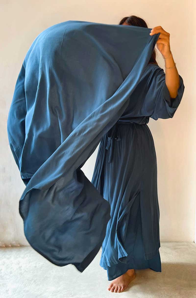 Person wearing a long blue robe against a plain background