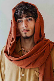 Man wearing a brown scarf and beige shirt against a plain background
