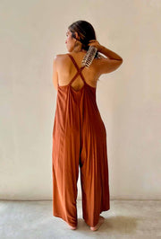 Woman wearing a rust-colored jumpsuit against a plain background