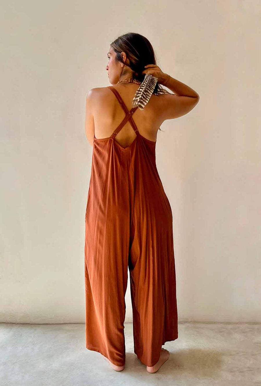 Woman wearing a rust-colored jumpsuit against a plain background