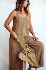 Woman wearing a brown slip dress holding a dried plant against a white background