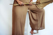 Person wearing a brown outfit holding a broom against a white background