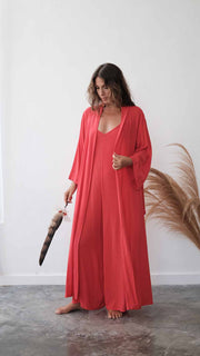Woman in a red dress holding a feather duster against a white wall.