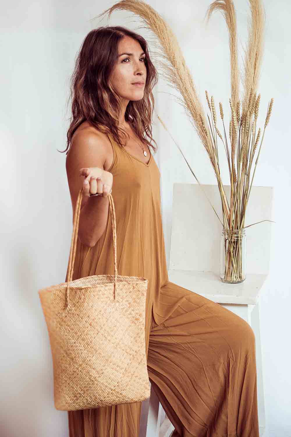 Woman holding a woven bag in a minimal indoor setting