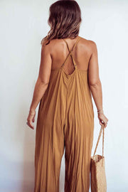 Woman wearing a mustard yellow jumpsuit holding a straw bag against a white background