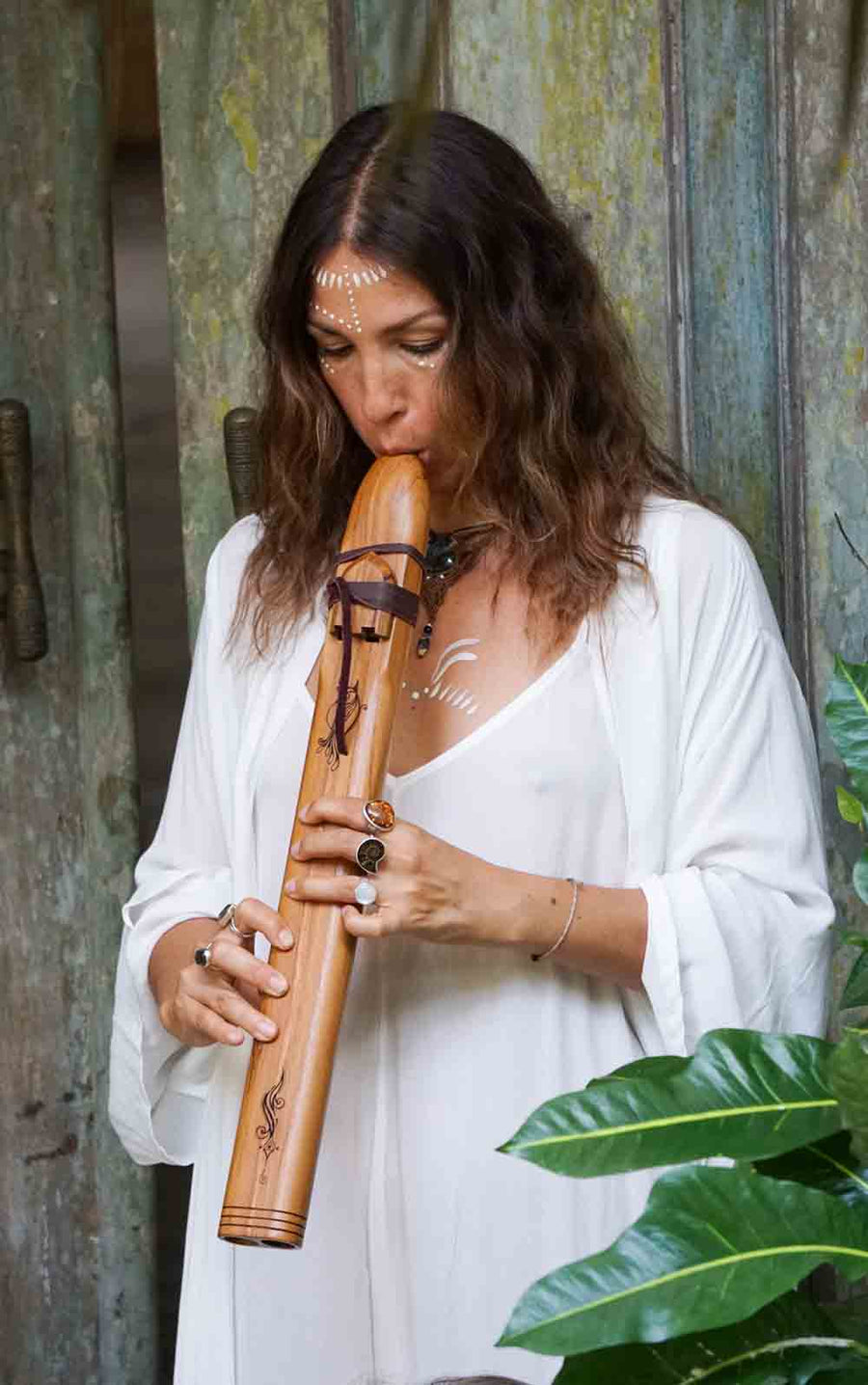 Woman playing a wooden flute against a rustic background