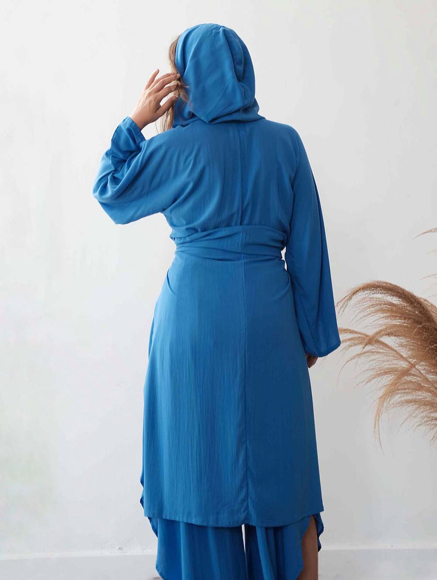 Woman wearing a blue dress with a hood against a white background