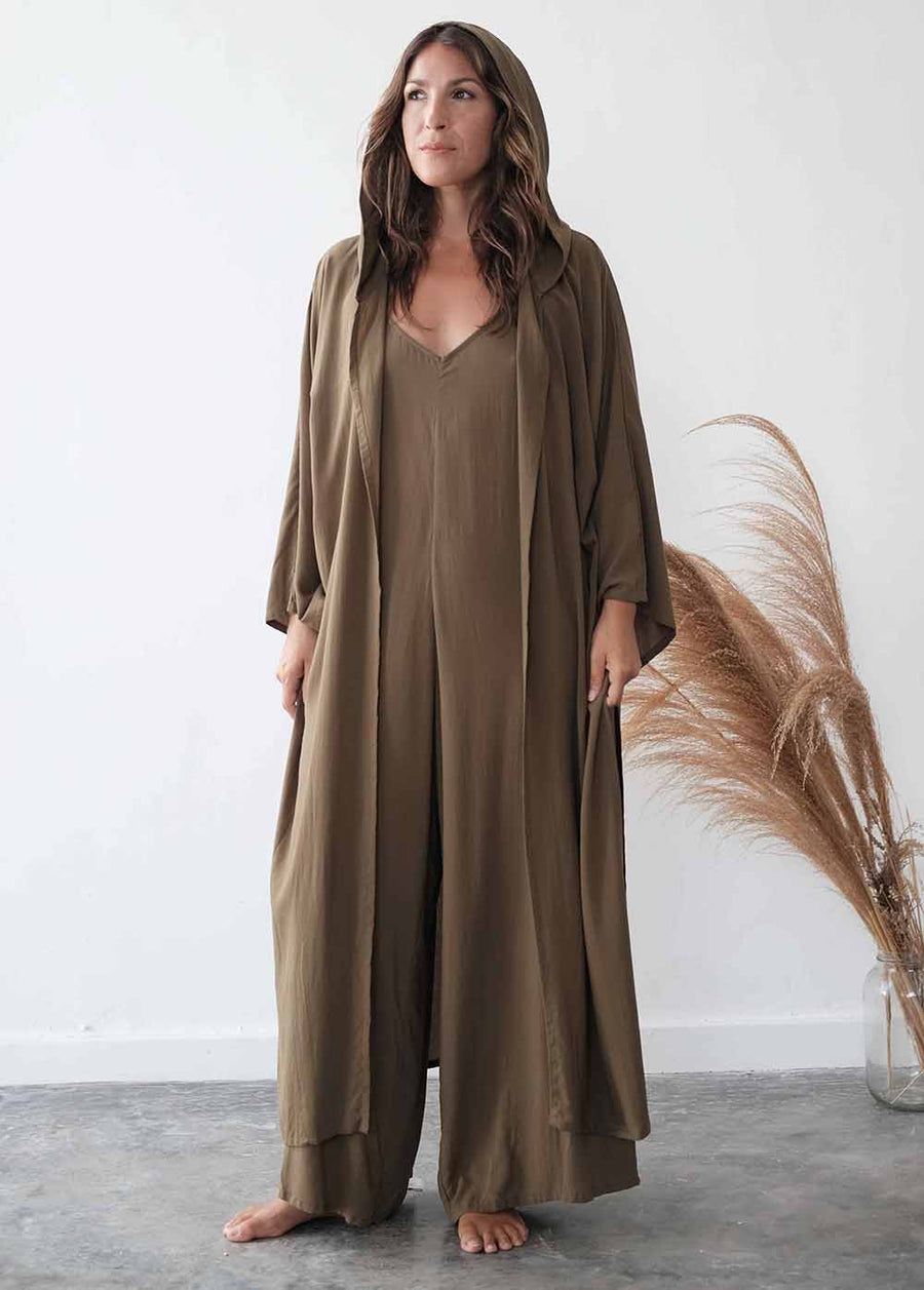 Woman wearing a long olive green dress with a matching jacket against a white background.