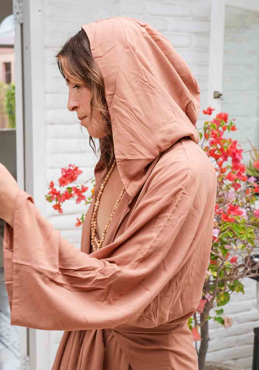 Woman wearing a peach-colored hijab and dress with a blurred background