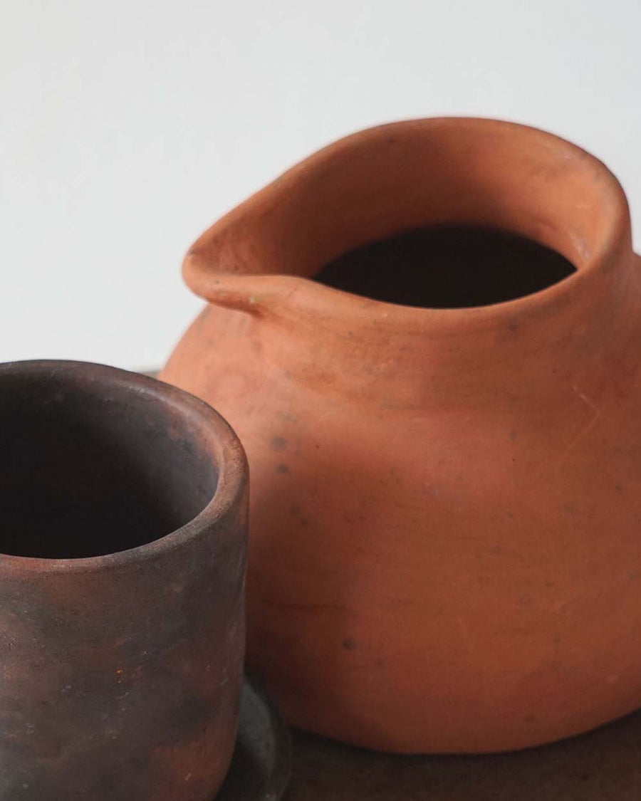Two terracotta pots, one larger and one smaller, on a neutral background.
