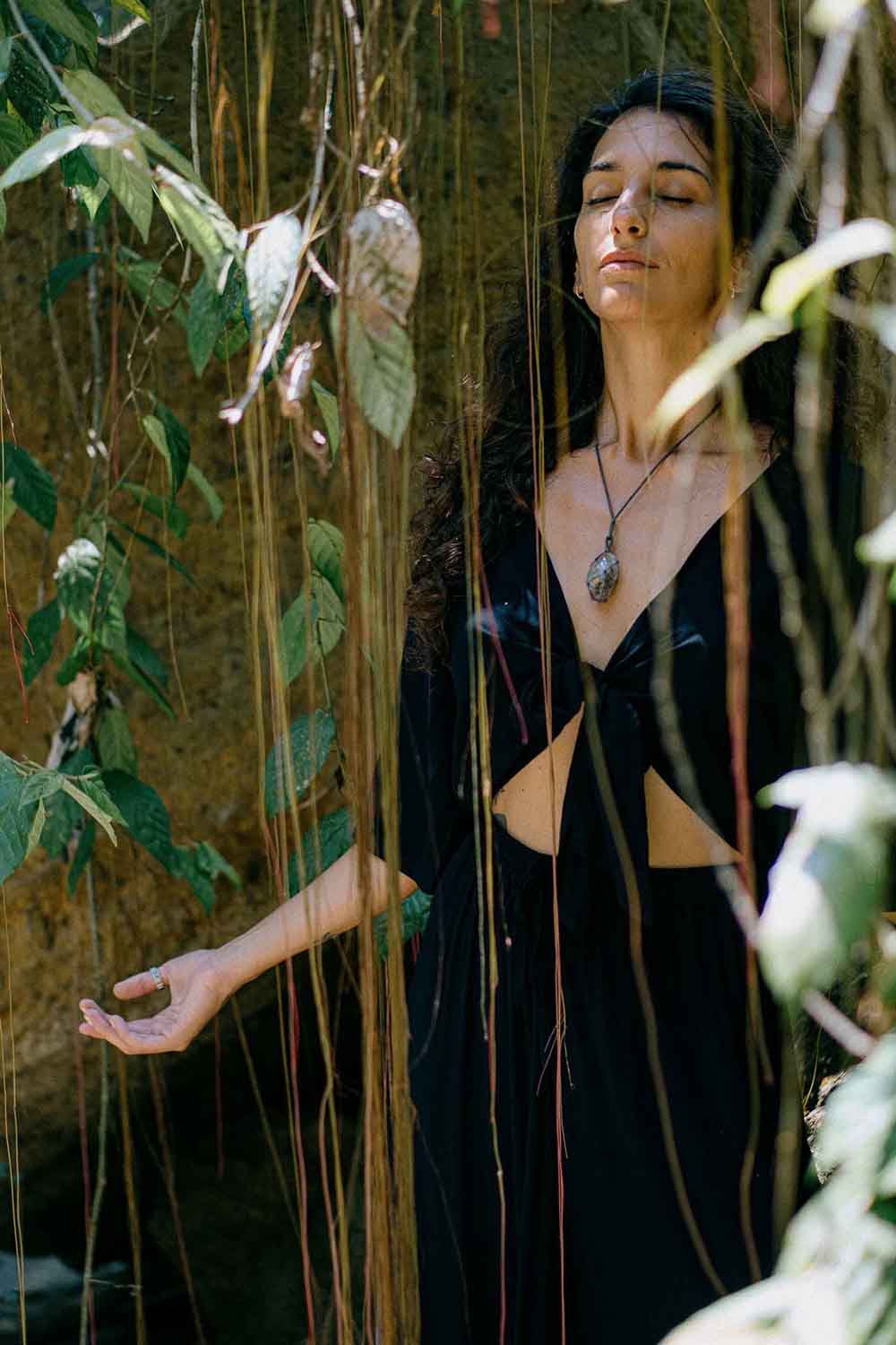 Woman in a black dress standing among plants