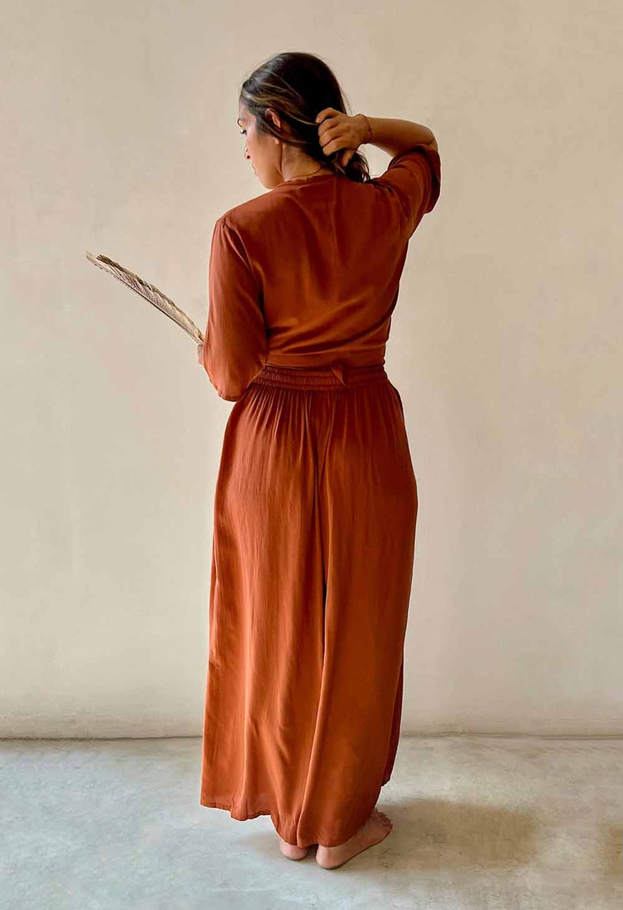 Woman in a rust-colored dress standing against a plain background