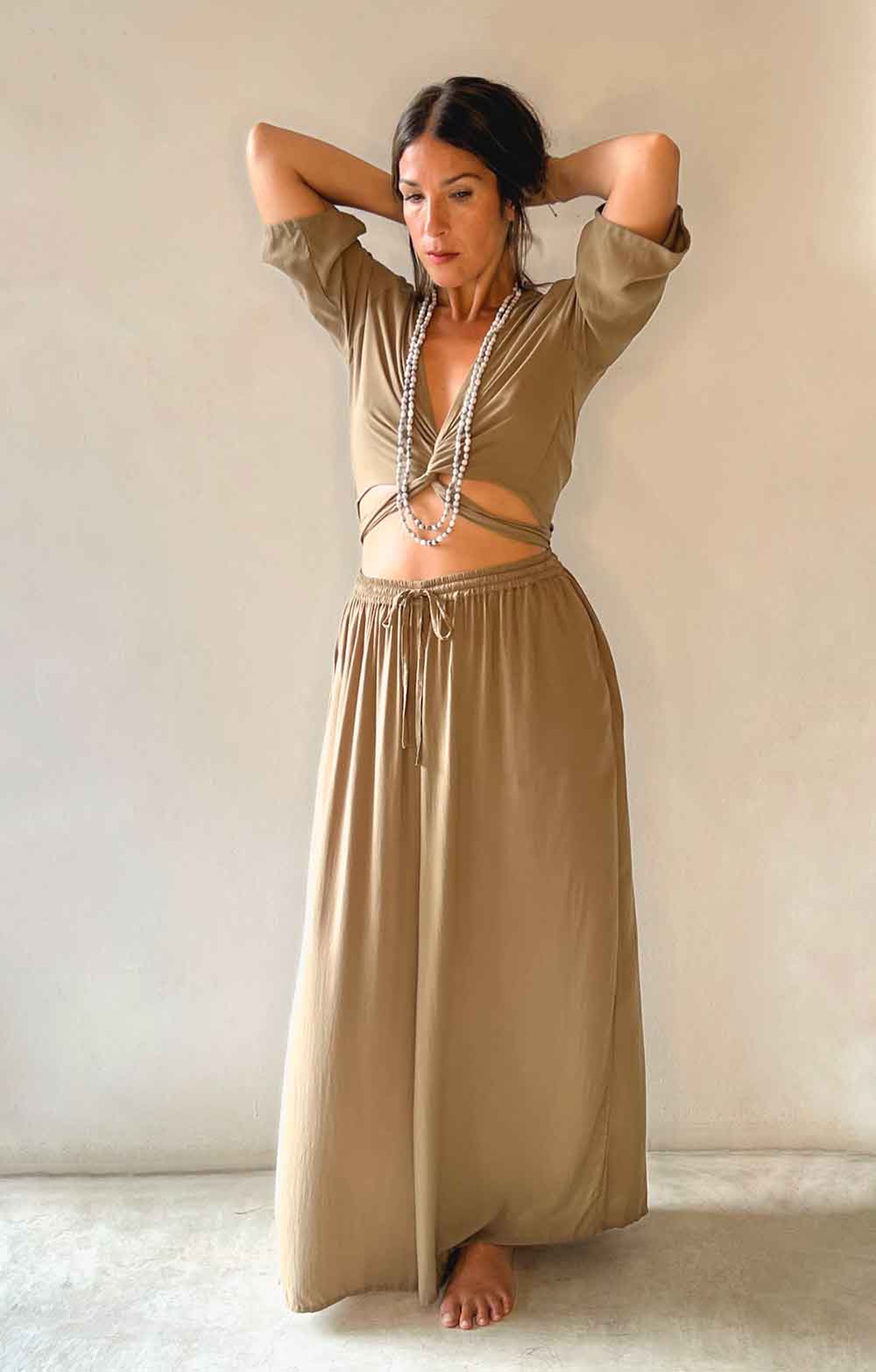 Woman wearing a beige top and long skirt against a plain background