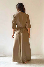 Woman wearing a long beige dress against a plain background
