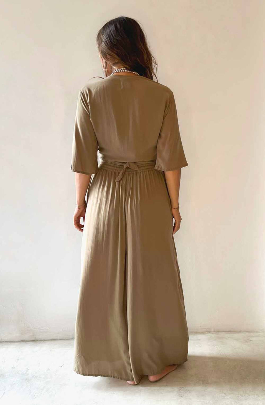 Woman wearing a long beige dress against a plain background