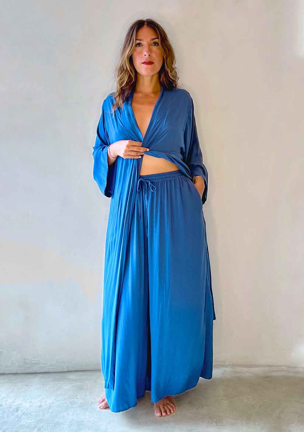 Woman wearing a blue robe and matching pants against a plain background