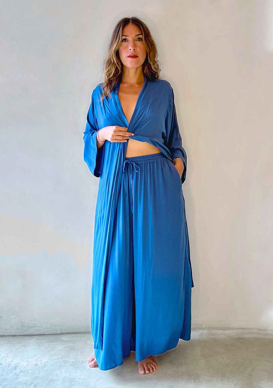 Woman wearing a blue robe and matching pants against a plain background