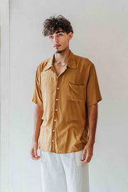 Man wearing a mustard yellow shirt with a plain background