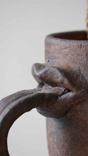 Close-up of a rustic metal mug with a handle on a light gray background