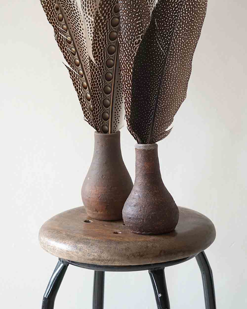 Decorative vase with textured surface on a wooden stool against a plain background