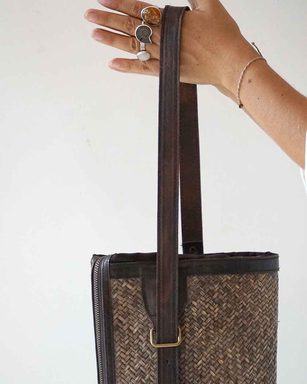 Hand holding a woven tote bag with a plain background